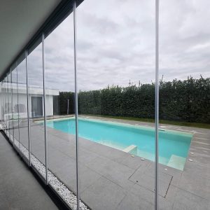 Piscina esterna vista da veranda vetrata.