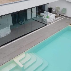 Piscina moderna accanto a vetrate.