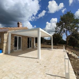 Terrazza con pergola bianca e cielo nuvoloso.