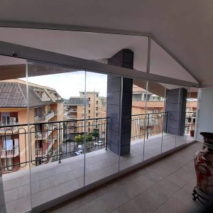 Balcone vetrato con vista su edifici residenziali.