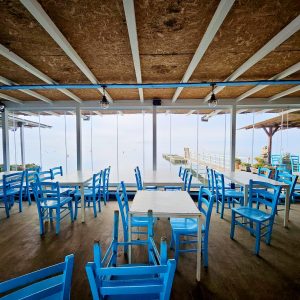 Sedie blu in ristorante con vista mare.