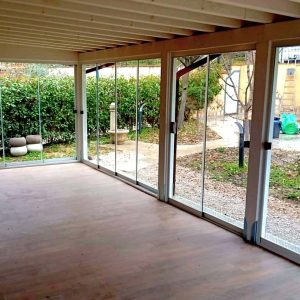 Veranda con vetrate affacciata su giardino.